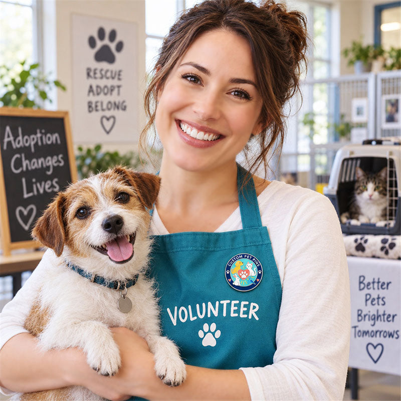 Animal shelter volunteer wearing a round pet pin on a teal apron while holding a dog
