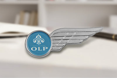 Custom Pilot Wing Pins Silver With Blue Enamel Center And 3D Fleur-De-Lis Design Featuring Custom Text 'OLP' In Private High School Academic Setting For Student Honor And Identity