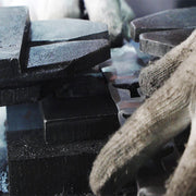 Factory worker performing precise trimming on stamped metal lapel pins, blanking each badge according to the custom shape design