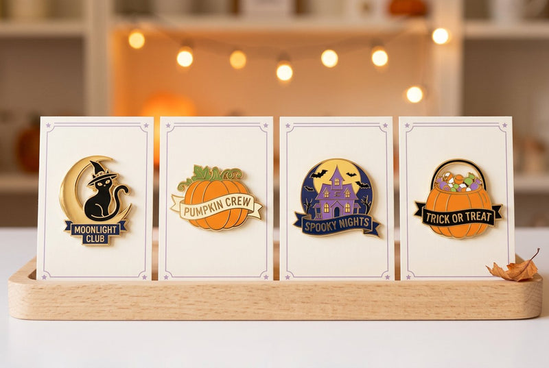 Original Halloween character pins displayed on matching backing cards for a seasonal shop collection