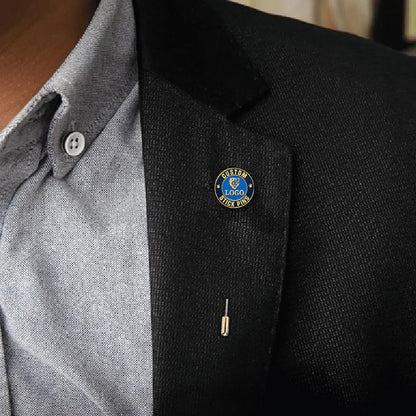 Custom stick pin with blue enamel featuring custom text, pinned on a dark suit lapel.