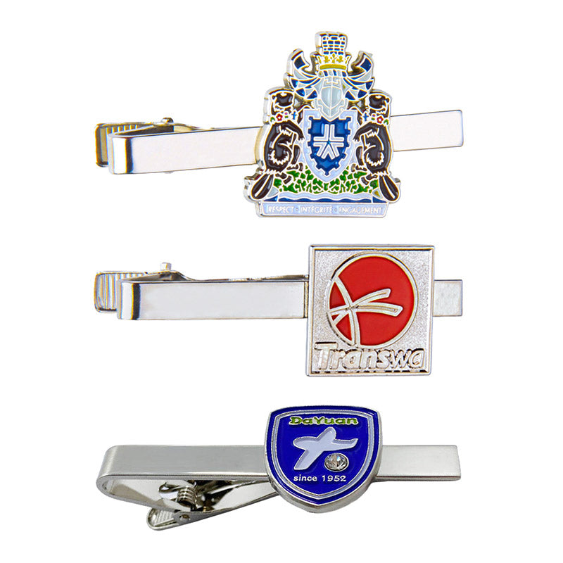 Display of three custom tie clips vertically arranged on white background, featuring various emblem designs including heraldic, abstract, and shield styles with custom text and logos for business customization.