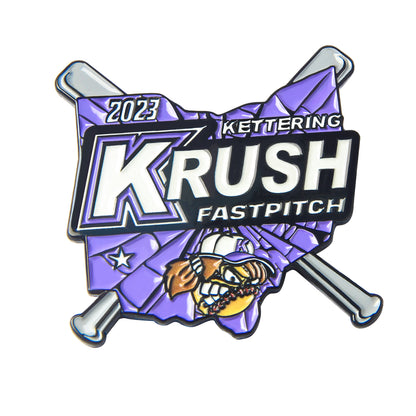 Custom baseball trading pin in a flag shape with a large letter K, a grinning cartoon mascot, and crossed silver bats, featuring custom team text.