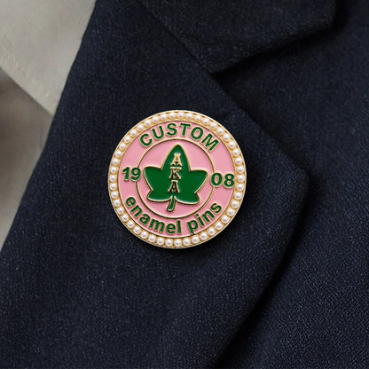 A premium pearl-rimmed AKA enamel pin pinned to a dark navy suit lapel, demonstrating an elegant on-garment look.