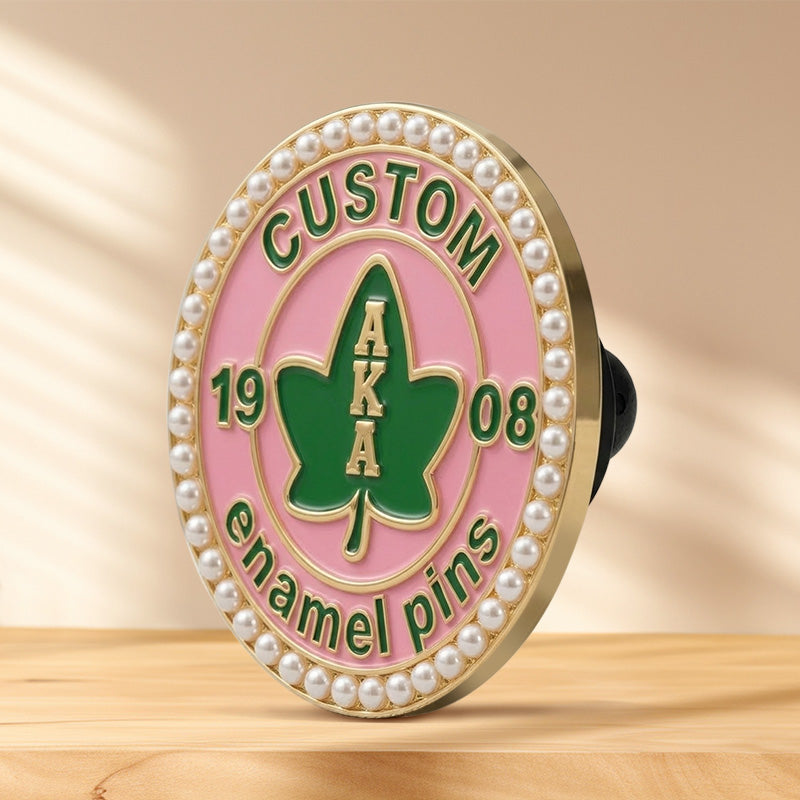 Side angle view of a custom round AKA pearl pin on a wooden surface, showing the gold-plated edge and details.