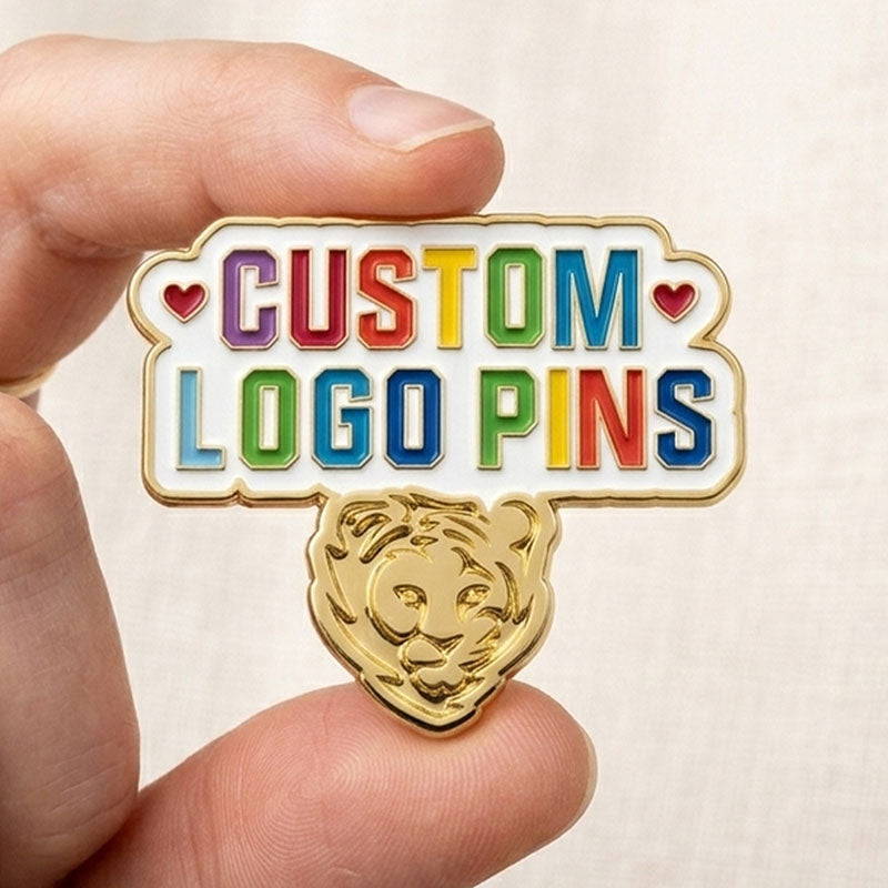 Hand holding a custom hard enamel pin in Gold plating to showcase its actual size and vibrant logo design