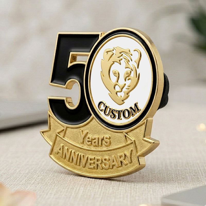 A side-angle perspective view of a custom 50th anniversary lapel pin in gold tone, showing the polished thickness of the black enamel number 50 and the white round tiger emblem insert above a textured milestone banner.