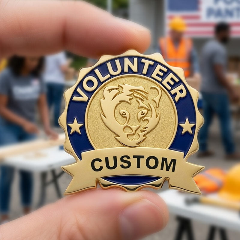 A close-up of a person holding a custom gold-tone volunteer recognition pin, featuring a textured golden center with a lion emblem, flanked by a blue enamel border and a prominent bottom ribbon banner.