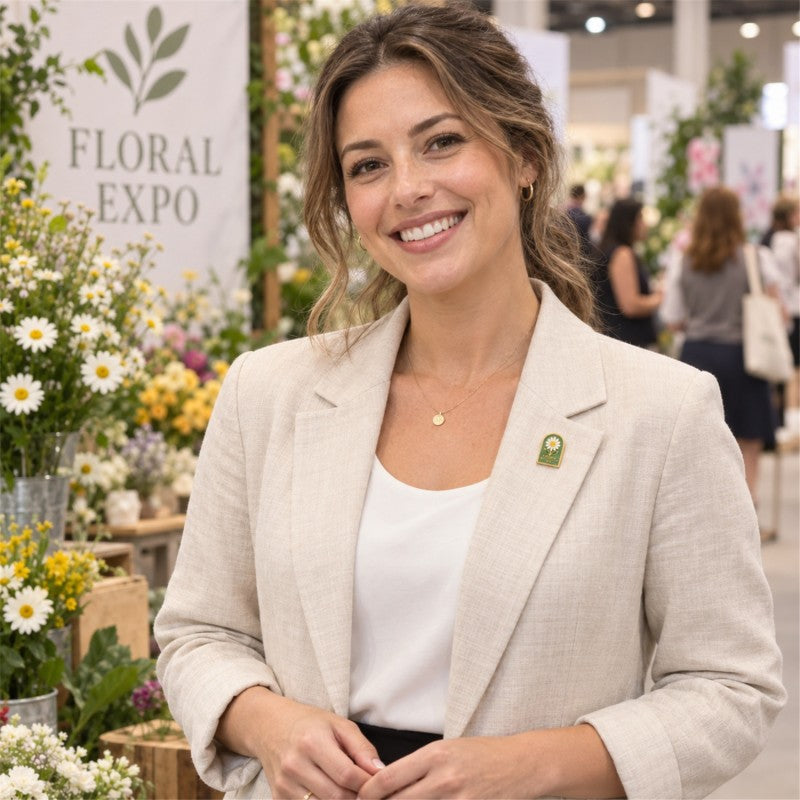 Woman wearing a green daisy lapel pin on a beige blazer at a floral expo