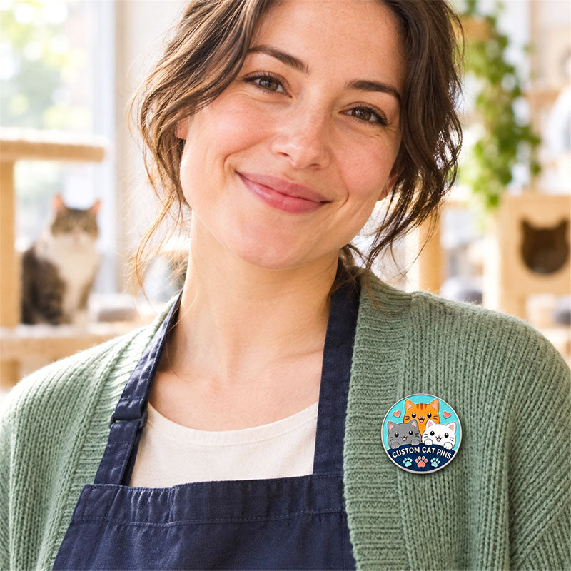 Woman wearing a round three-cat enamel pin on a green cardigan in a cat-themed room