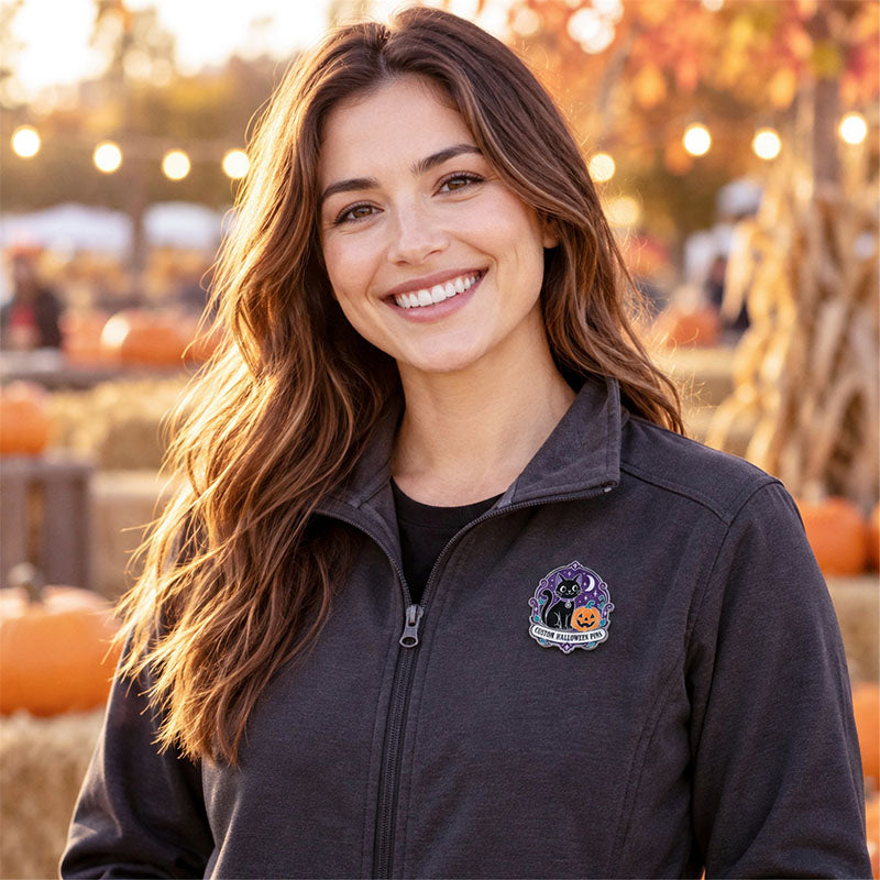 Woman wearing a black cat and pumpkin Halloween pin on a dark jacket at a fall event