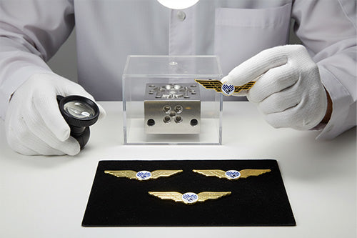 Airline Wing Pins Undergoing Magnified Inspection of Precision Mold Featuring Gold Wings with 3D Detail and White and Blue Roundel for Quality Assurance in Precision Manufacturing