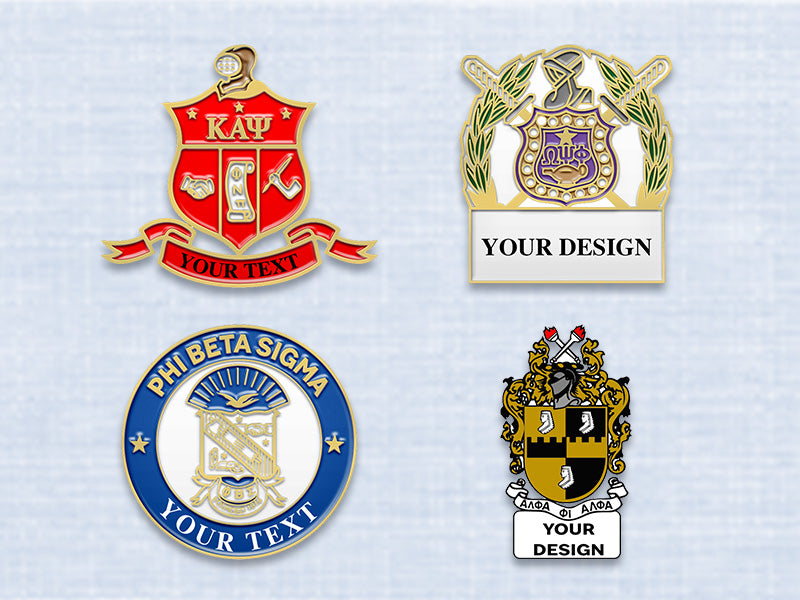 Fraternity pins with Gold plating showcasing Alpha Phi Alpha, Kappa Alpha Psi, Omega Psi Phi, and Phi Beta Sigma designs on a fabric background