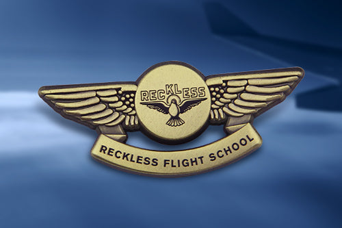 Custom Pilot Wing Pins For Flying School Recognition Featuring Gold Stylized Wings And Circular Center With Custom Text 'RECKLESS' And 'RECKLESS FLIGHT SCHOOL' And Bird Design On Blue Gradient Background