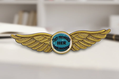 Custom Pilot Wing Pins Gold With Stylized Wings And Circular Center Featuring Custom Text 'THEY PROMISED HER THE MOON' In Private High School Bookshelf Background For Academic Achievement And Recognition