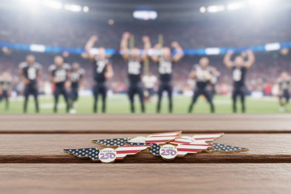 Patriotic Lapel Pins with American Flag Design and Custom Text '250' Displayed on Wooden Surface Against Blurred Sports Stadium Scene Featuring Celebrating Athletes For Sports Event Recognition And Commemoration