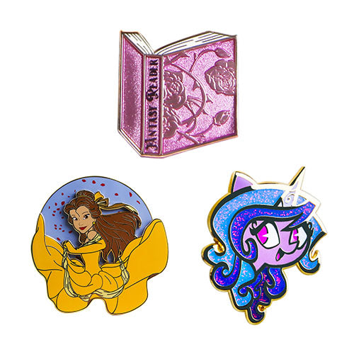 Three colorful pins featuring a book, a character in yellow dress, and a cartoon face