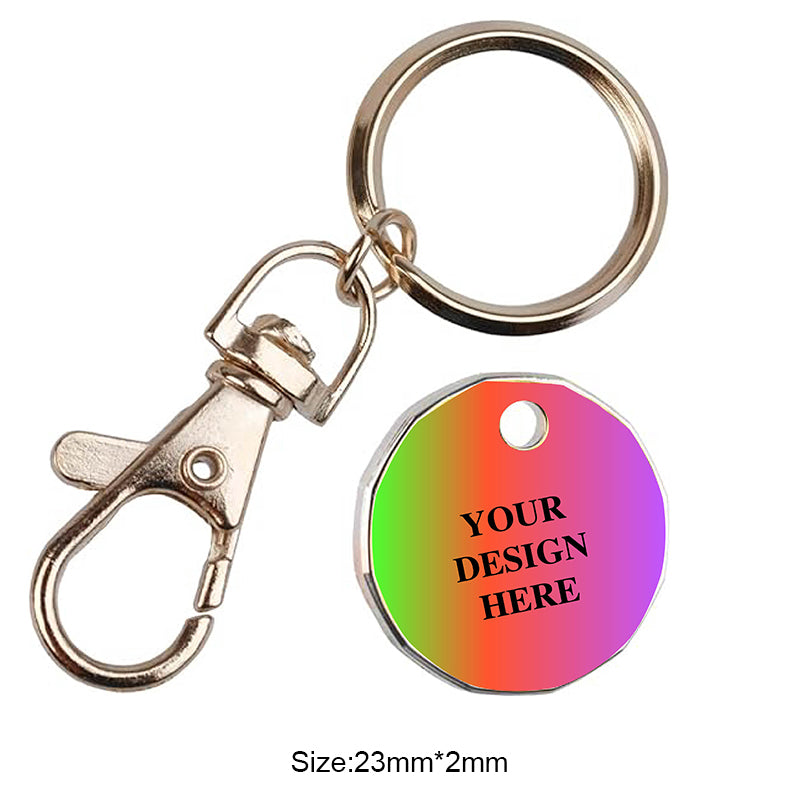 A rainbow gradient trolley token keychain with a metal clasp, shown on a white background. The token features placeholder text "YOUR DESIGN HERE".