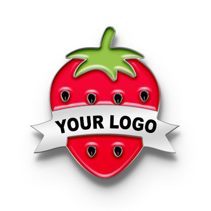 A pin with a metal clasp shaped like a strawberry with a space for a custom logo, predominantly red with a green leaf on top and a banner ribbon for personalization.