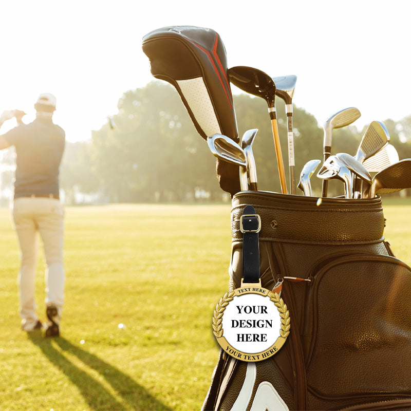 Personalized golf bag tag with custom text areas, attached to a black golf bag with silver clubs on a sunny golf course with a person swinging, emphasizing customization and sporty atmosphere for golf enthusiasts.